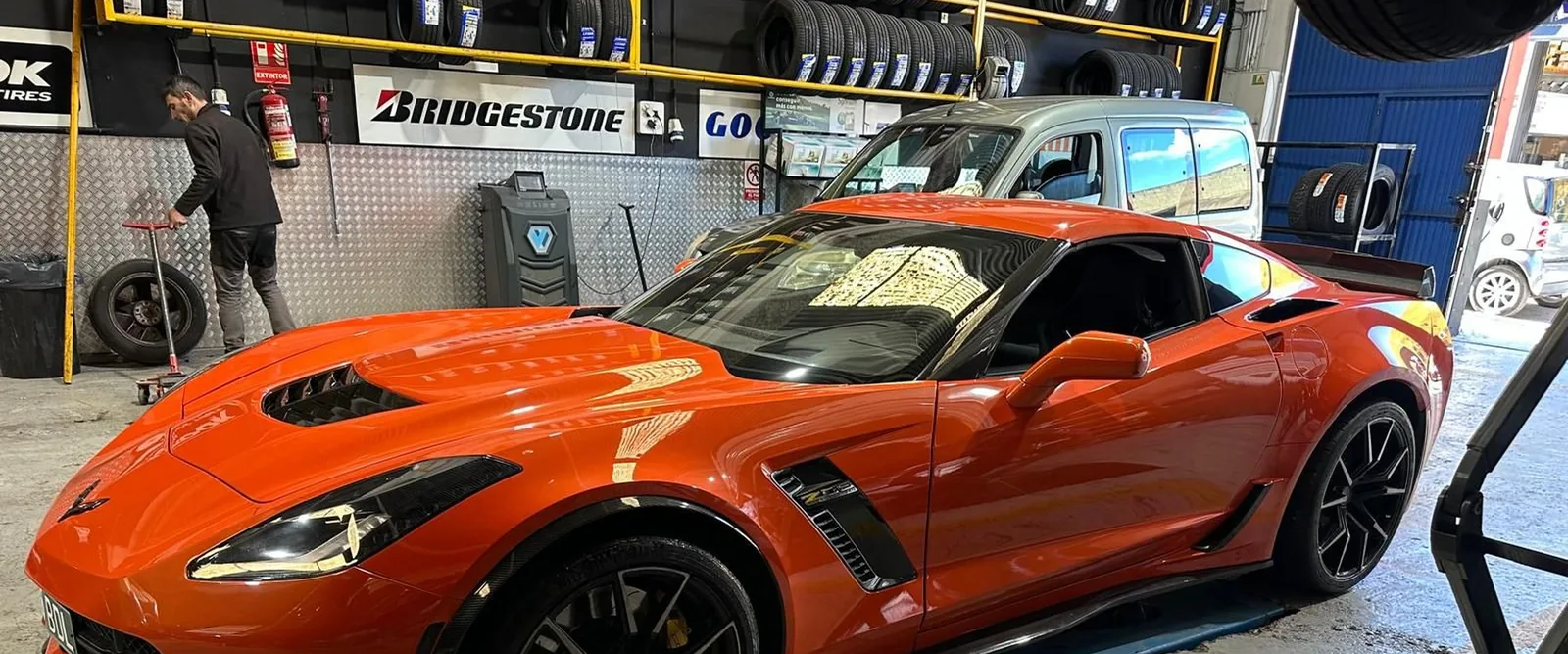 Coche deportivo naranja rodeado de ruedas en el taller Dautos Car, en Marbella